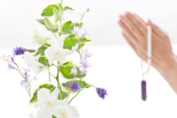 生花と手をあわせる女性